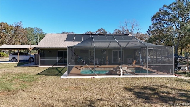 rear view of house with a lanai, a lawn, a carport, and solar panels