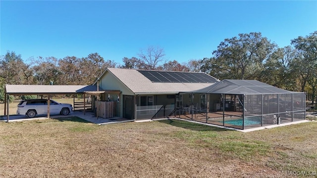 rear view of house featuring a lawn, glass enclosure, and a swimming pool