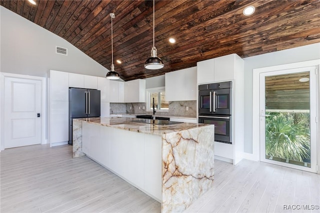 kitchen with decorative backsplash, light stone counters, high quality fridge, white cabinetry, and hanging light fixtures