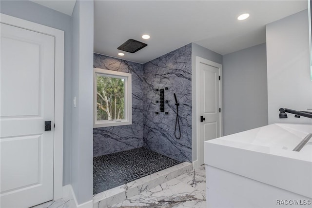 bathroom featuring tiled shower and sink