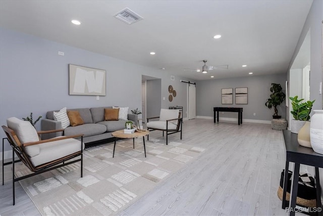 living area with light wood finished floors, visible vents, recessed lighting, and a barn door
