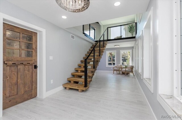 interior space featuring light wood-type flooring, a high ceiling, and a chandelier