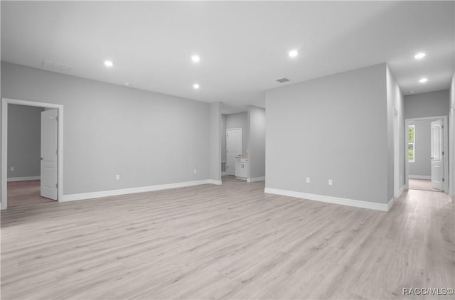 unfurnished living room featuring recessed lighting, baseboards, and light wood-type flooring