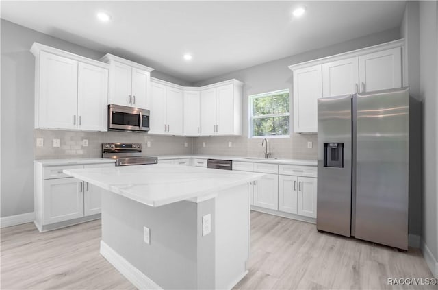 kitchen featuring a sink, white cabinets, stainless steel appliances, and light wood-style flooring