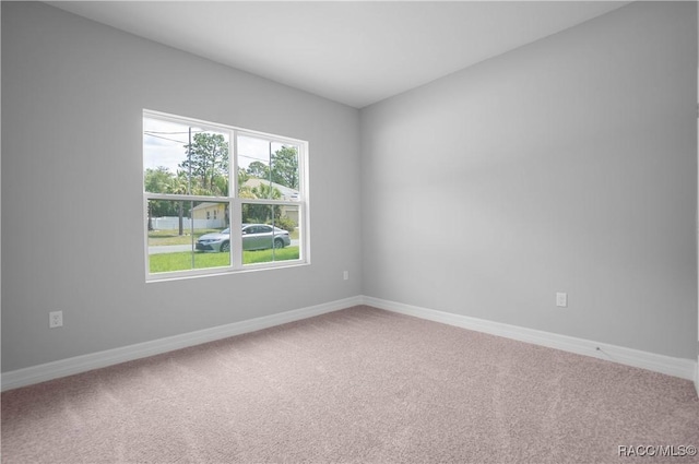 carpeted empty room featuring baseboards
