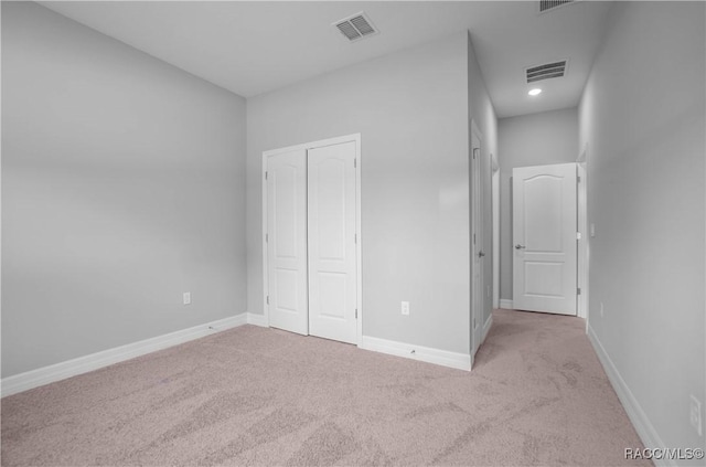 unfurnished bedroom with baseboards, visible vents, carpet, and a closet