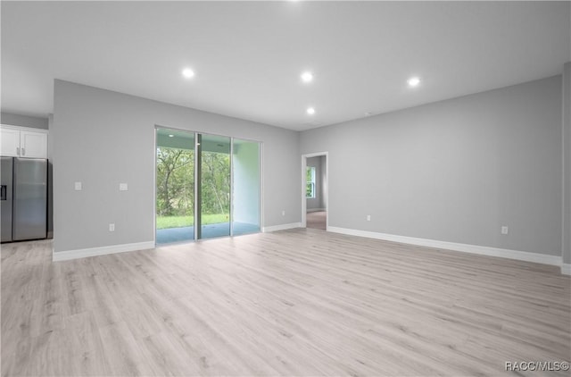 unfurnished living room with light wood-type flooring, recessed lighting, and baseboards