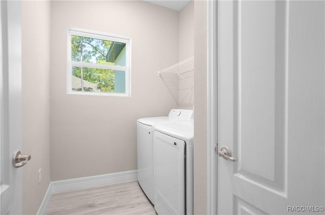 clothes washing area with baseboards, laundry area, light wood-style flooring, and washer and dryer