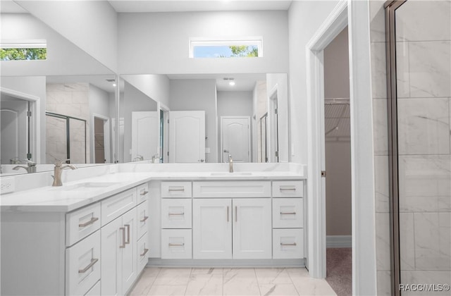 bathroom with double vanity, a shower stall, a sink, and marble finish floor