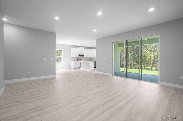 unfurnished living room featuring baseboards, recessed lighting, and light wood-style flooring