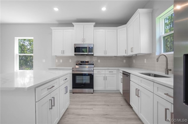 kitchen with a sink, stainless steel appliances, recessed lighting, and white cabinetry