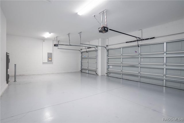 garage featuring a garage door opener, electric panel, and concrete block wall
