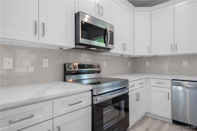 kitchen with decorative backsplash, white cabinetry, light stone counters, light wood finished floors, and appliances with stainless steel finishes