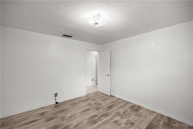 unfurnished room featuring light wood-type flooring and a textured ceiling