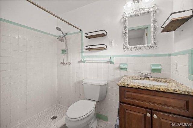 bathroom featuring toilet, vanity, tile walls, and tiled shower