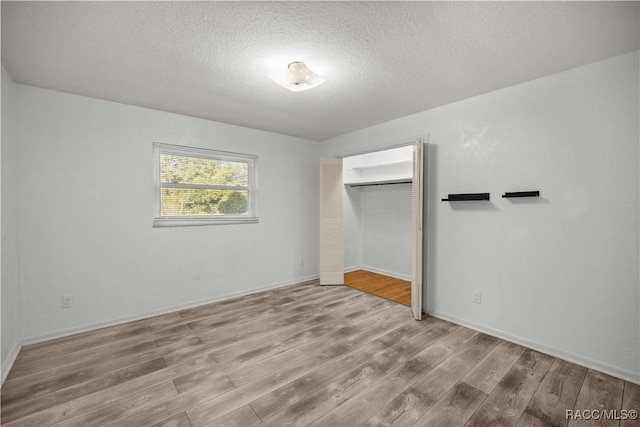 unfurnished bedroom featuring light hardwood / wood-style floors, a textured ceiling, and a closet