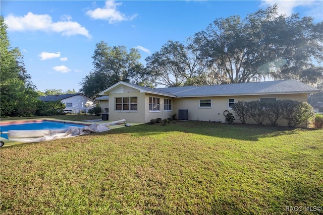 rear view of property with central AC and a lawn