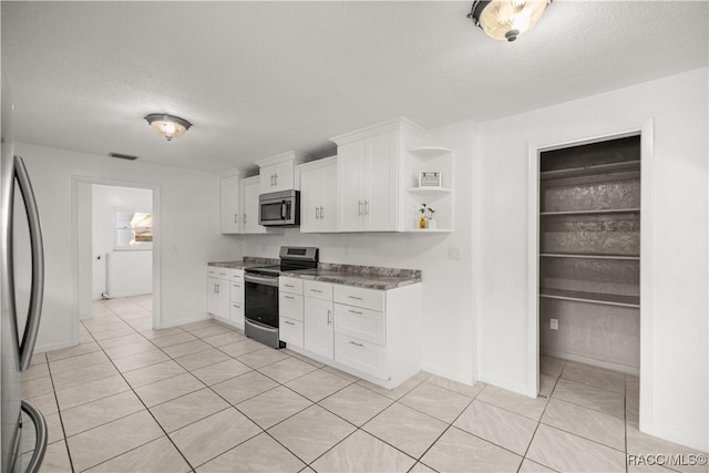 kitchen with white cabinets, stainless steel appliances, and a textured ceiling