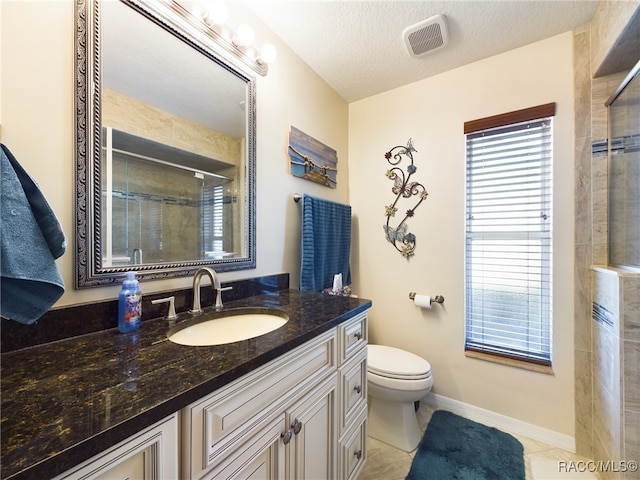 bathroom with vanity, a shower with door, tile patterned flooring, toilet, and a textured ceiling