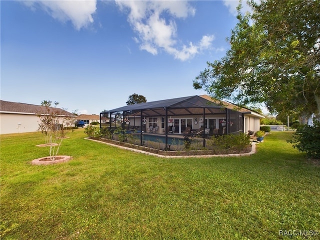 rear view of property with glass enclosure and a yard