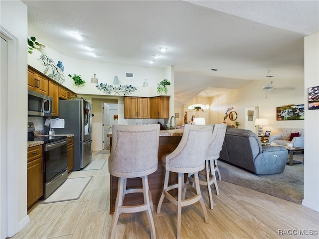 kitchen with light stone countertops, a kitchen breakfast bar, backsplash, stainless steel appliances, and sink