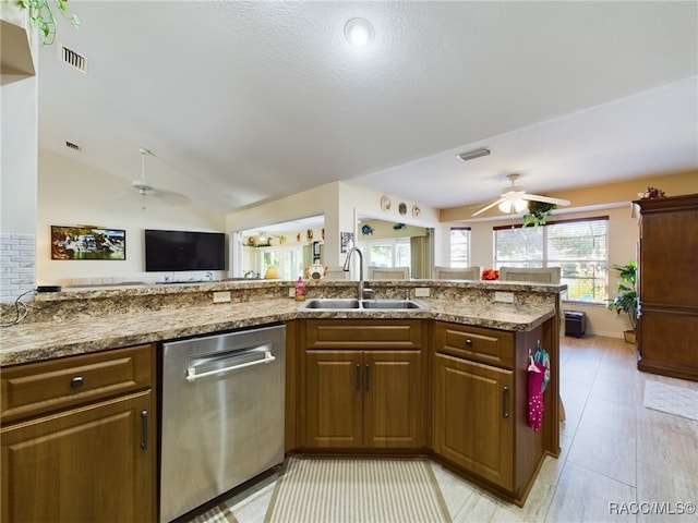 kitchen with light stone countertops, stainless steel dishwasher, vaulted ceiling, sink, and light tile patterned floors