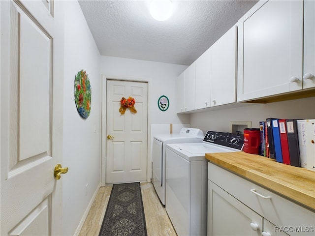 washroom with cabinets, light wood-type flooring, a textured ceiling, and separate washer and dryer