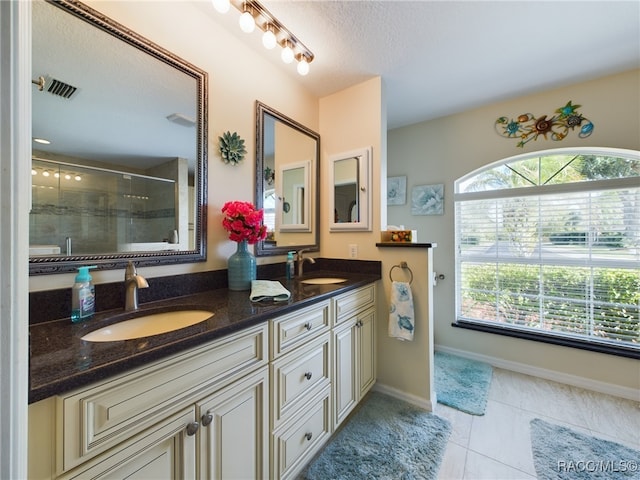 bathroom featuring tile patterned flooring, vanity, a shower with shower door, and a textured ceiling