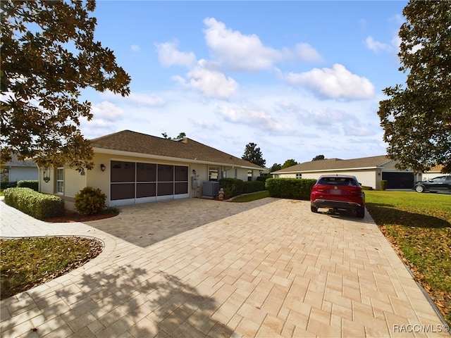 ranch-style house featuring a front lawn, a garage, and central AC unit