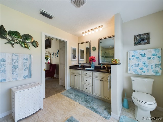 bathroom with a textured ceiling, vanity, toilet, and a shower with door