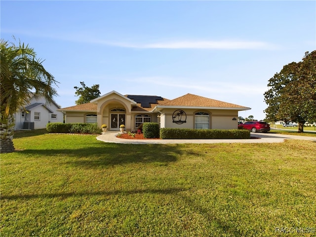 view of front of home featuring a front lawn, central AC unit, and solar panels