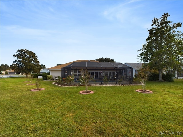 rear view of house with glass enclosure and a yard