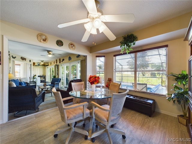 dining area featuring a textured ceiling, light hardwood / wood-style floors, plenty of natural light, and ceiling fan