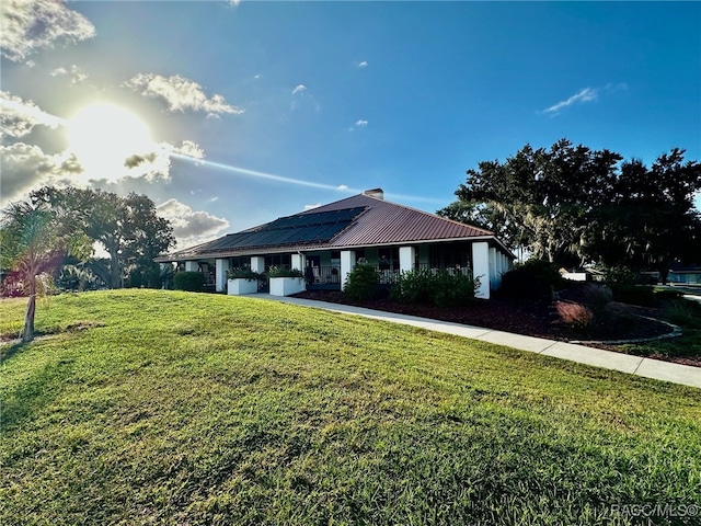 view of front facade featuring solar panels and a front lawn