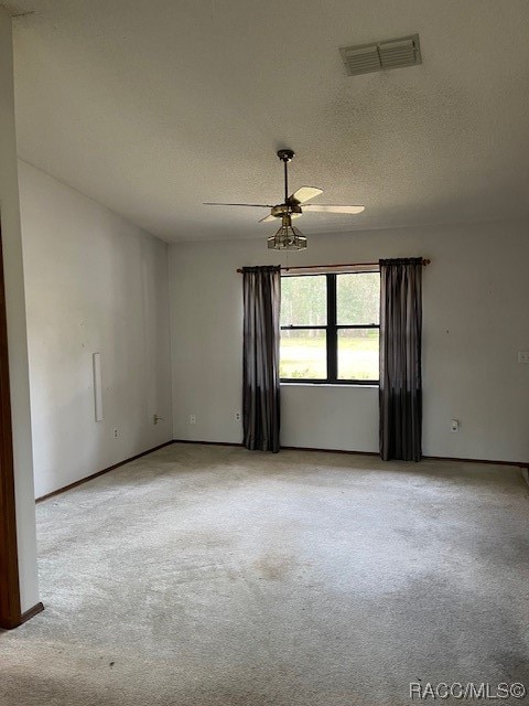 carpeted spare room featuring a textured ceiling and ceiling fan