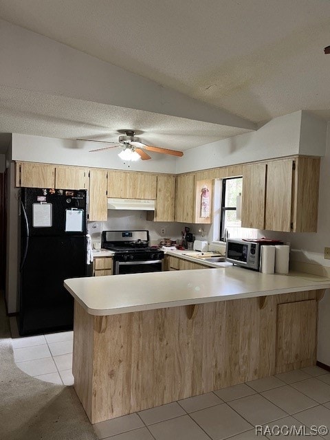 kitchen featuring kitchen peninsula, light tile patterned flooring, lofted ceiling, and stainless steel appliances