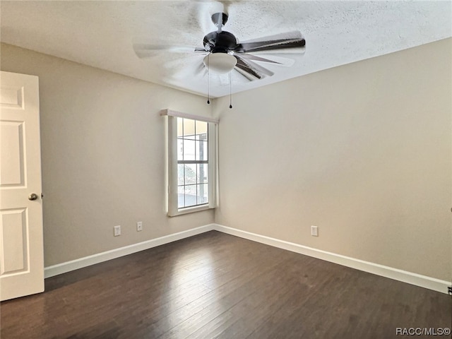 empty room featuring ceiling fan, dark wood-type flooring, and a textured ceiling