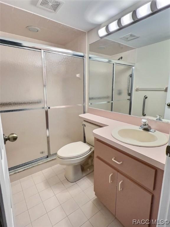 2058 Forest Dr, Inverness, FL 34453 - full bathroom featuring vanity, a stall shower, toilet, and tile patterned flooring