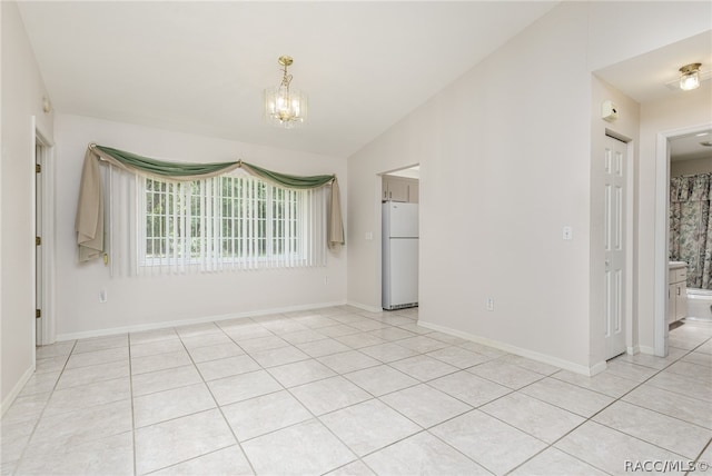 tiled empty room with a notable chandelier and lofted ceiling