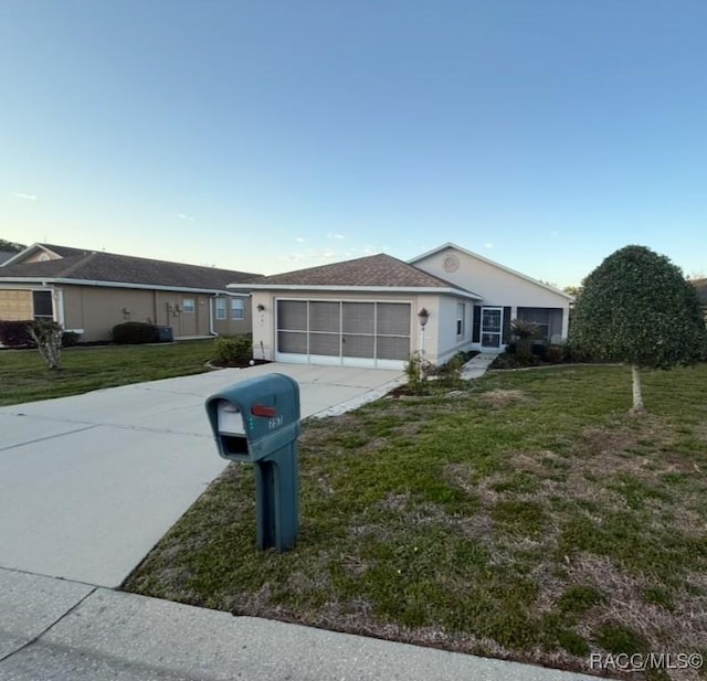 single story home with stucco siding, a front lawn, an attached garage, and driveway