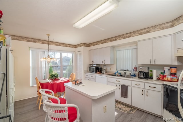 kitchen featuring an inviting chandelier, a kitchen island, white appliances, white cabinets, and hardwood / wood-style flooring