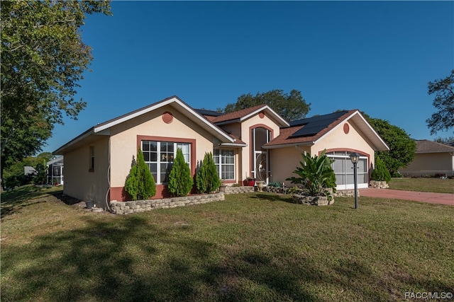 ranch-style home featuring solar panels, a garage, and a front yard