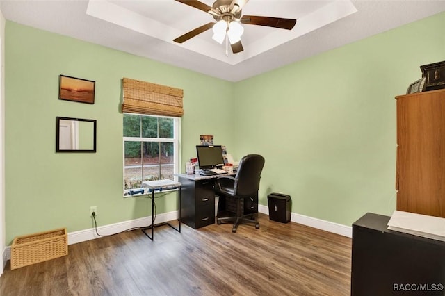 home office with dark wood-style floors, baseboards, and a tray ceiling