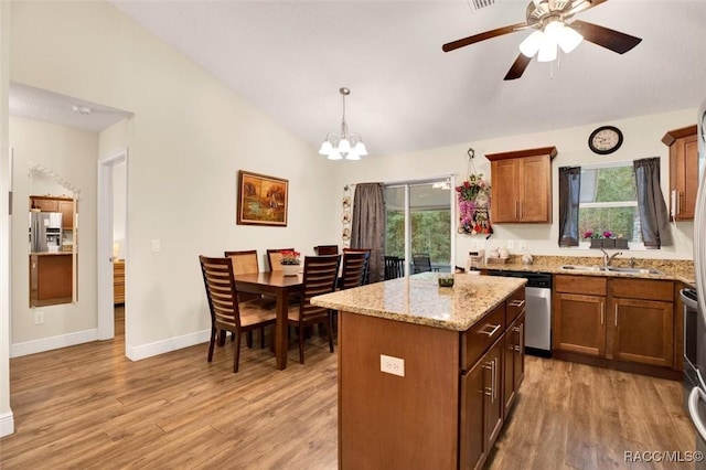 kitchen featuring a sink, vaulted ceiling, hanging light fixtures, appliances with stainless steel finishes, and a center island