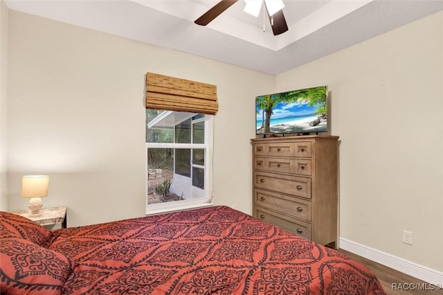 bedroom with ceiling fan, wood finished floors, and baseboards