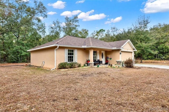 ranch-style home featuring an attached garage, covered porch, driveway, and stucco siding