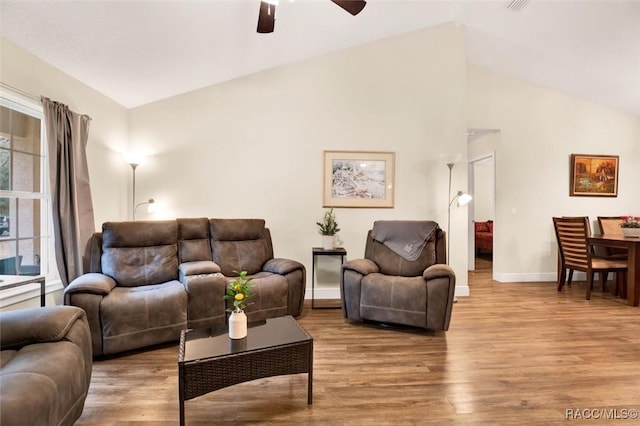 living area featuring lofted ceiling, light wood-style floors, baseboards, and a ceiling fan