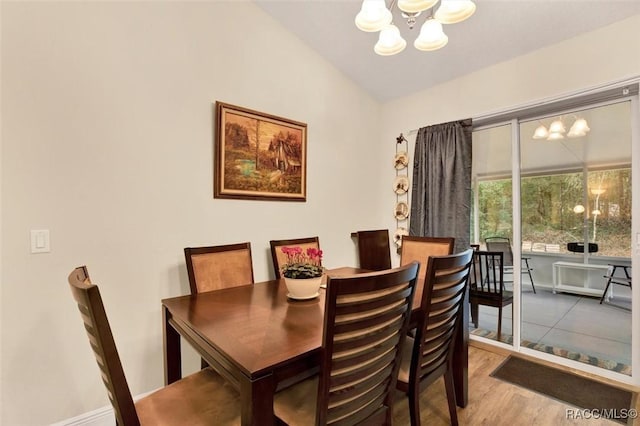 dining space featuring a chandelier, vaulted ceiling, and wood finished floors