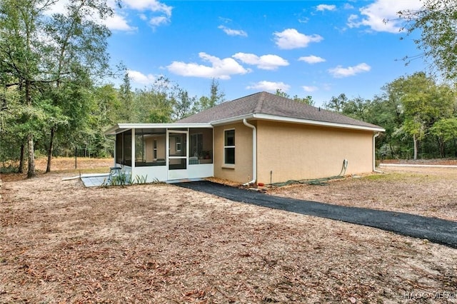 rear view of house featuring a sunroom and stucco siding