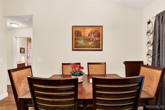 dining space featuring dark wood-style flooring and baseboards